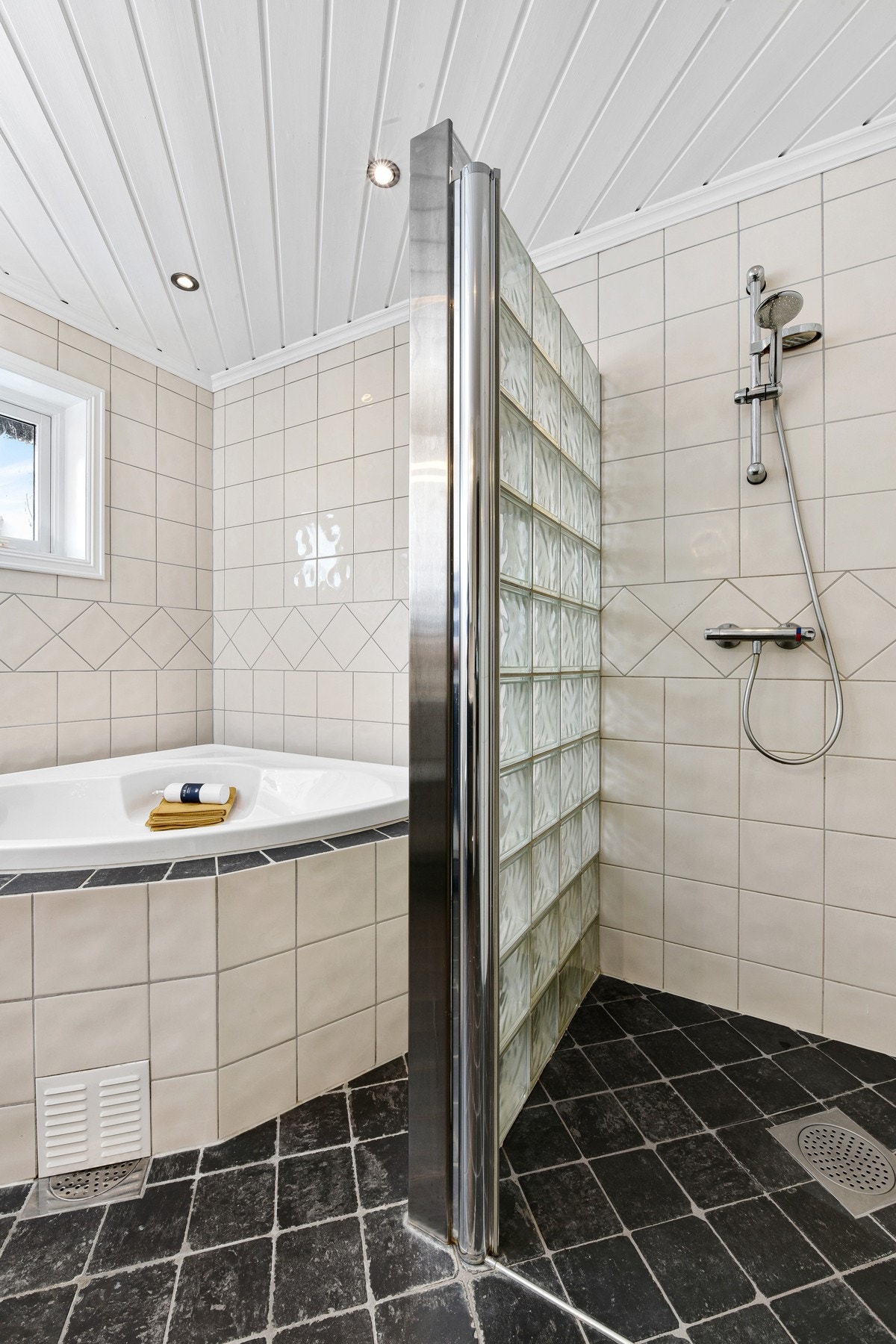Badet er innredet med badekar og en dusjnisje med vegg av glassbyggerstein. Galleribilde