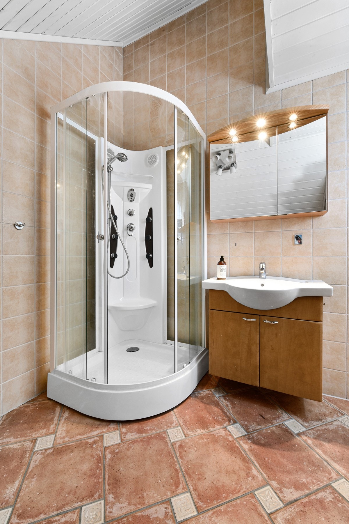 Badet i loftetasjen har fliser på gulv og vegger. Rommet har en heldekkende servant og et dusjkabinett. Galleribilde