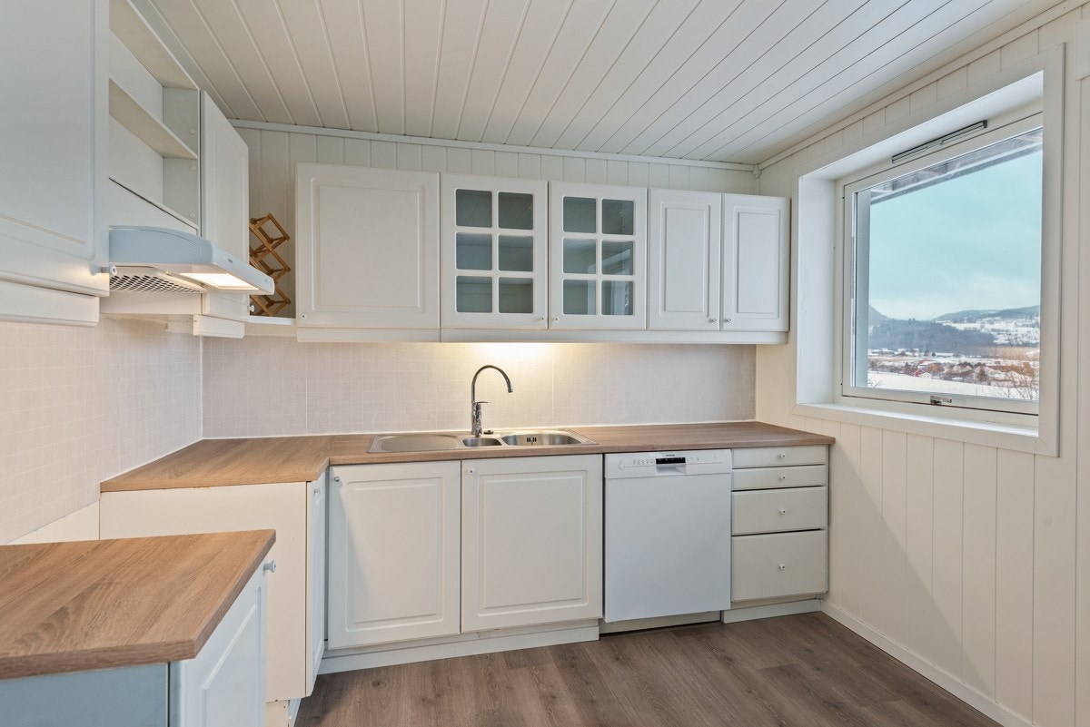 Innredningen har profilerte fronter, vitrineskap og laminatbenkeplate, med våtromsplater på veggene i bakkant. Det er ventilator over kokesone og opplegg for oppvaskmaskin. Galleribilde