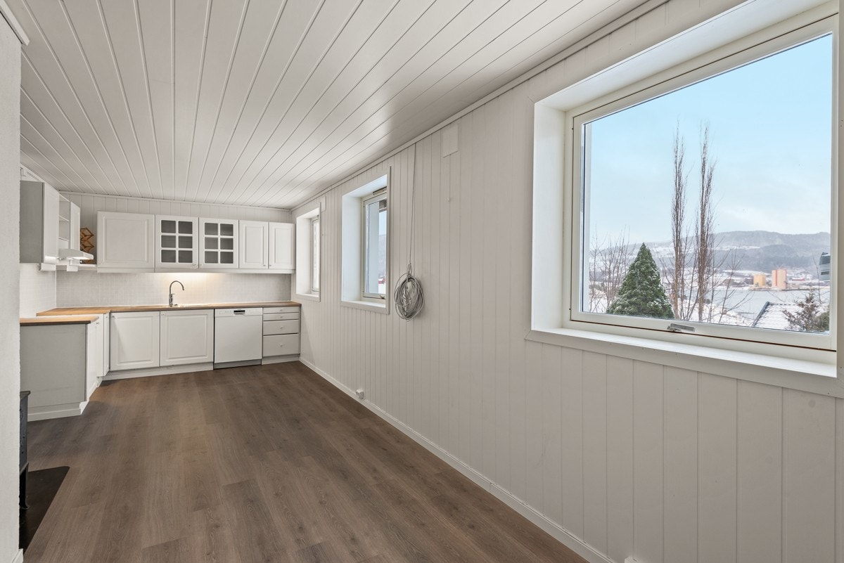 Kjøkkeninnredningen er lys, som panelveggene, og består av overskap og benkeskap i vinkelform. Galleribilde