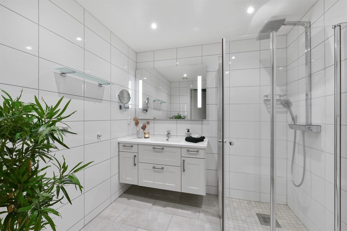 Det praktiske, pene badet ble oppgradert med nye gulvfliser i 2018 og har ellers fliser på veggene, gulvvarme og downlights. Galleribilde