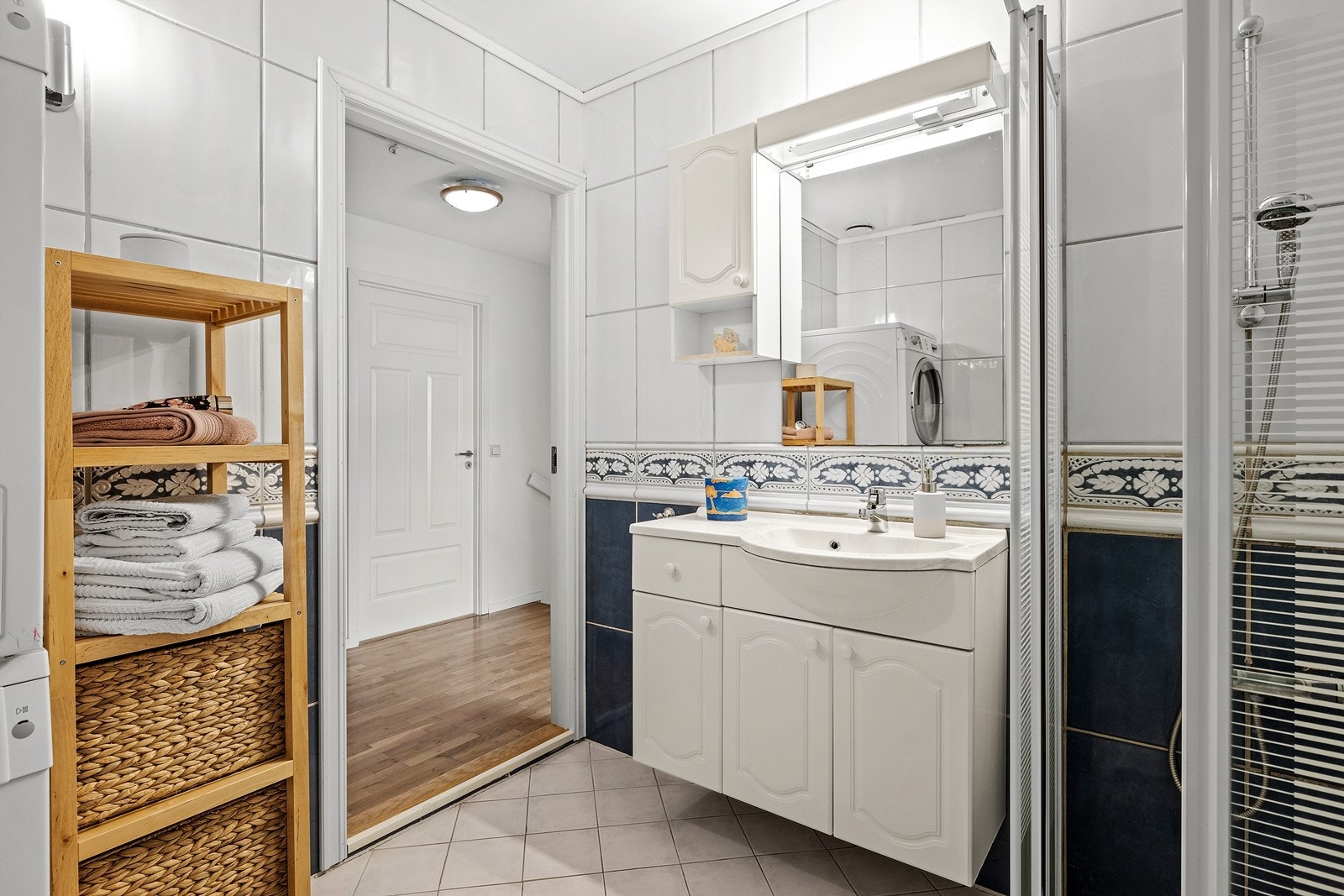 Flislagt baderom med heldekkende servant, underskap, dusjhjørne og opplegg for vaskemaskin og tørketrommel. Varme i gulv Galleribilde