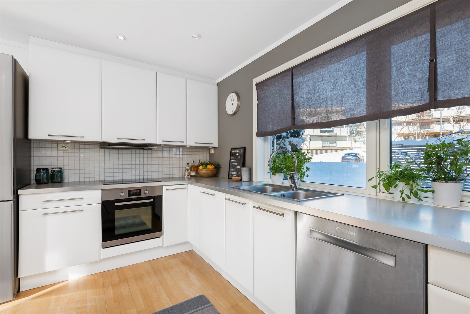 Kjøkkenet har takhøy innredning med hvite, glatte fronter og en laminert benkeplate med nedfelt oppvaskkum. Galleribilde