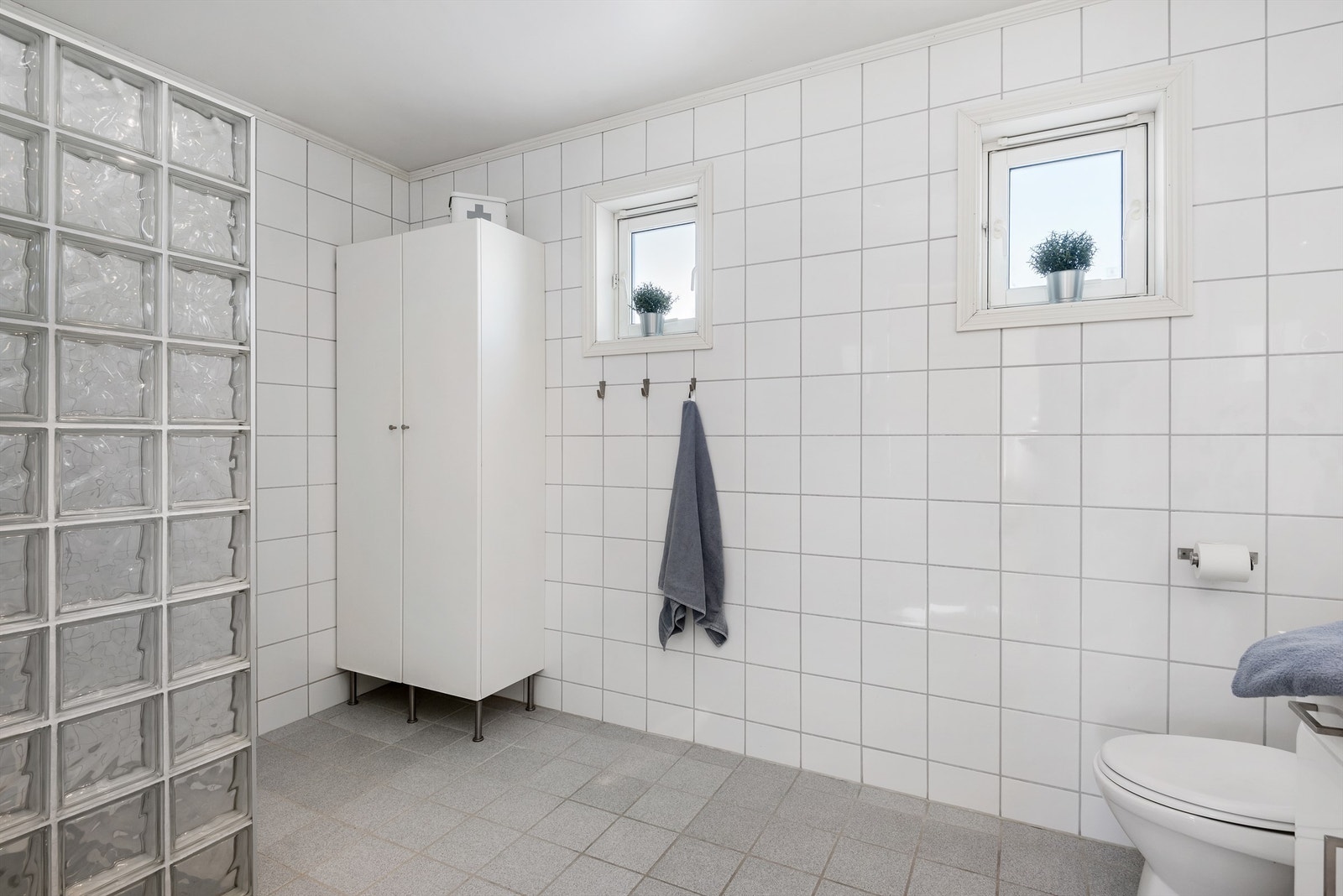 Badet i andre etasje har fliser på gulv og vegger, samt gulvvarme, downlights, toalett, dusjnisje og servantinnredning. Galleribilde