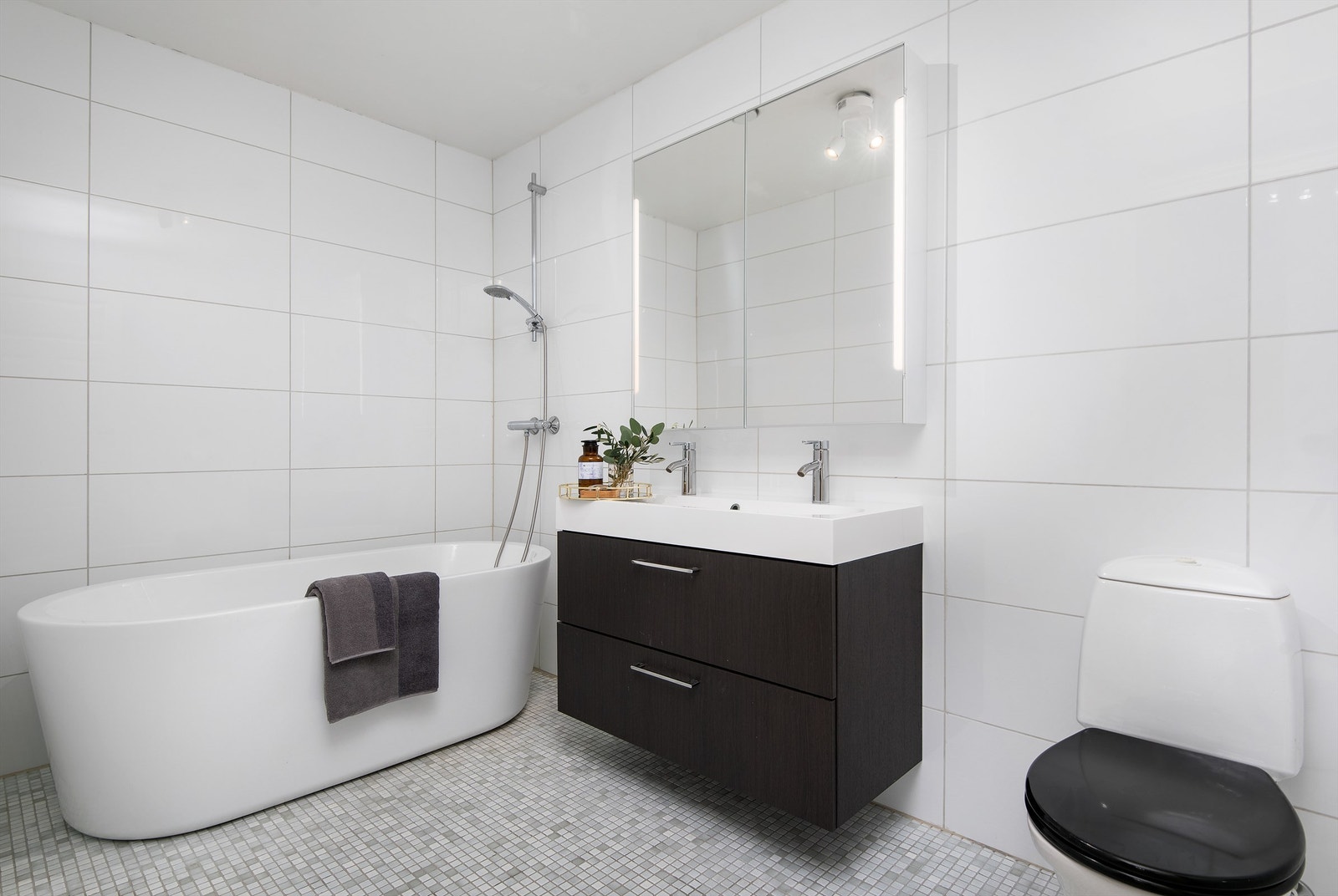 Badet i underetasjen har flislagte overflater, gulvvarme, deilig badekar, stilig innredning og et frittstående toalett Galleribilde