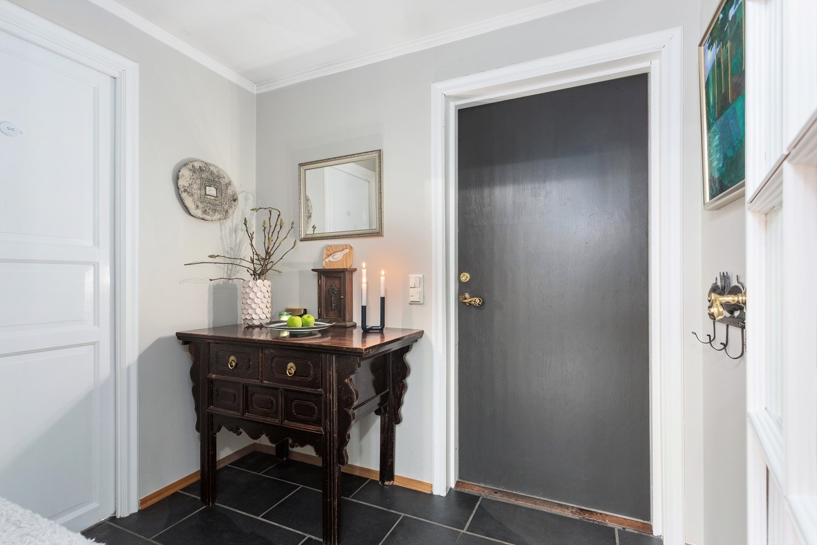 Den lyse entreen har mørke fliser på gulvet og plass til å sette fra seg sko og henge fra seg yttertøy på knaggrekke. Galleribilde