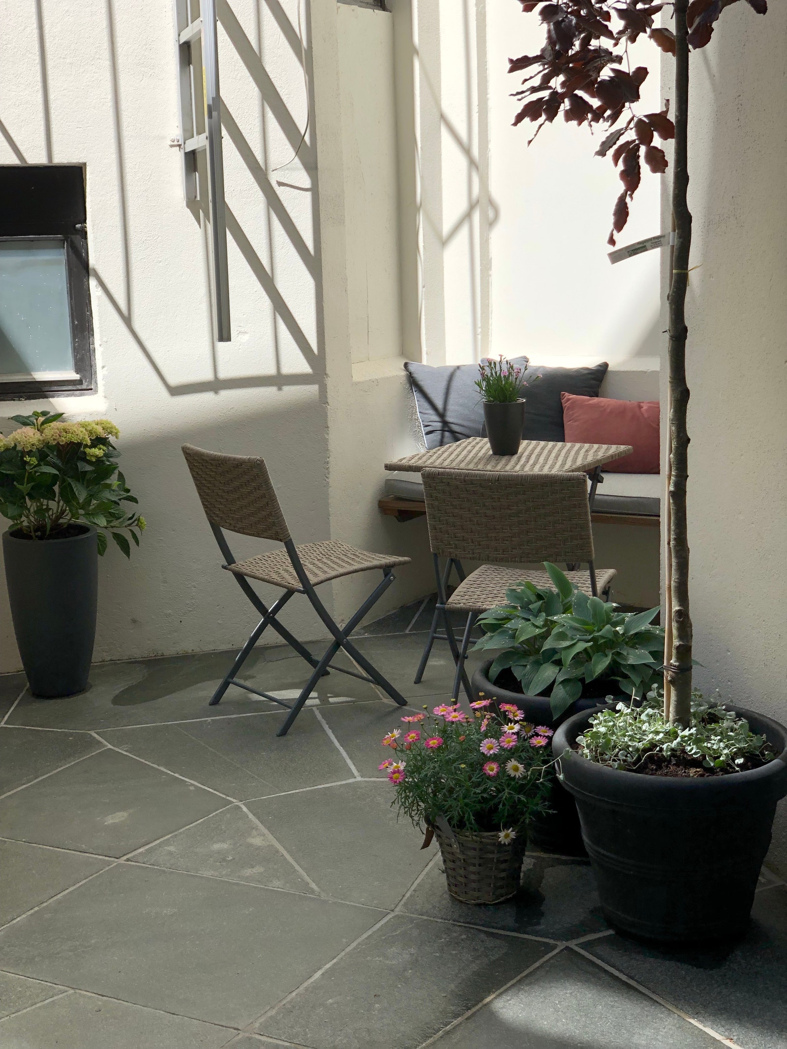 I bakgården står en benk med tilgjengeliege puter samt bord og stoler. Galleribilde