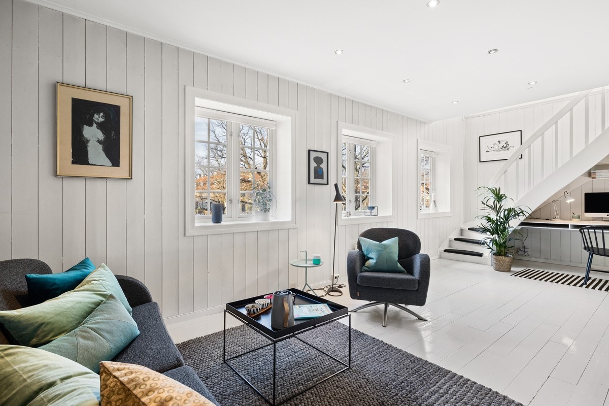 Hvitmalte panelvegger og malte, originale tregulv gir stuen et klassisk uttrykk. Galleribilde