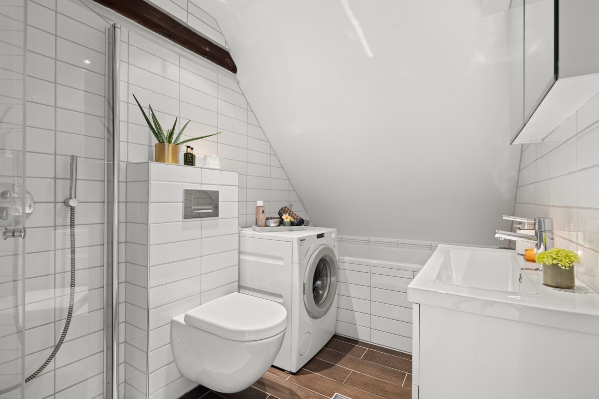 Badet er lekkert og fremstår med hvite veggfliser og mørke gulvfliser med underliggende gulvvarme. Galleribilde