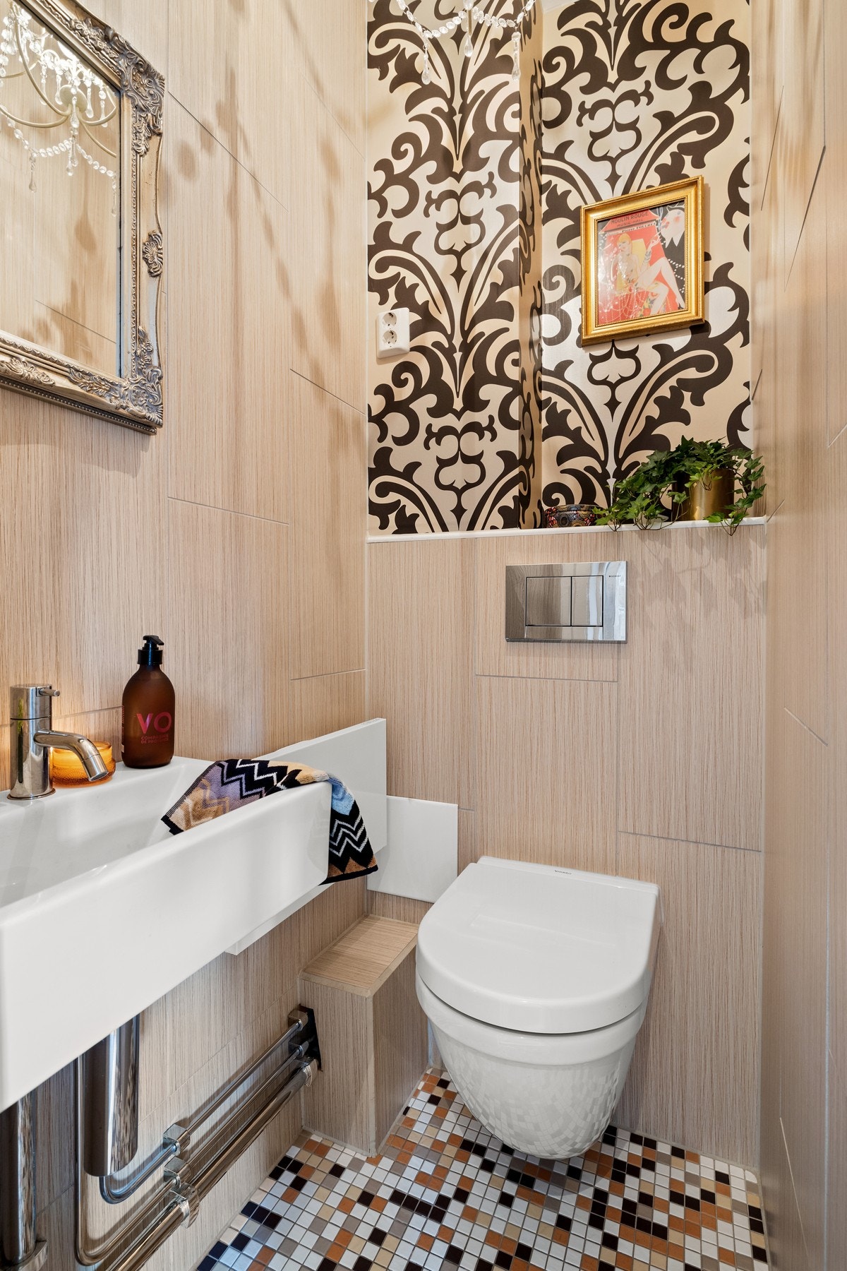 Gjestetoalettet fremstår moderne og innbydende. Toalettet har fliser på gulv og vegger og inneholder vegghengt klosett og servant. Galleribilde