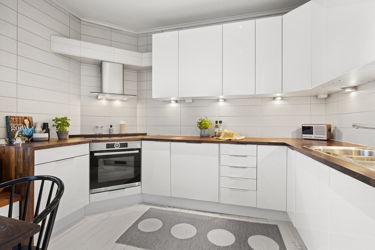 Integrerte hvitevarer som stekeovn med nedfelt keramisk koketopp, oppvaskmaskin og kjøl/frys gir kjøkkenet er rent og pent uttrykk. Galleribilde