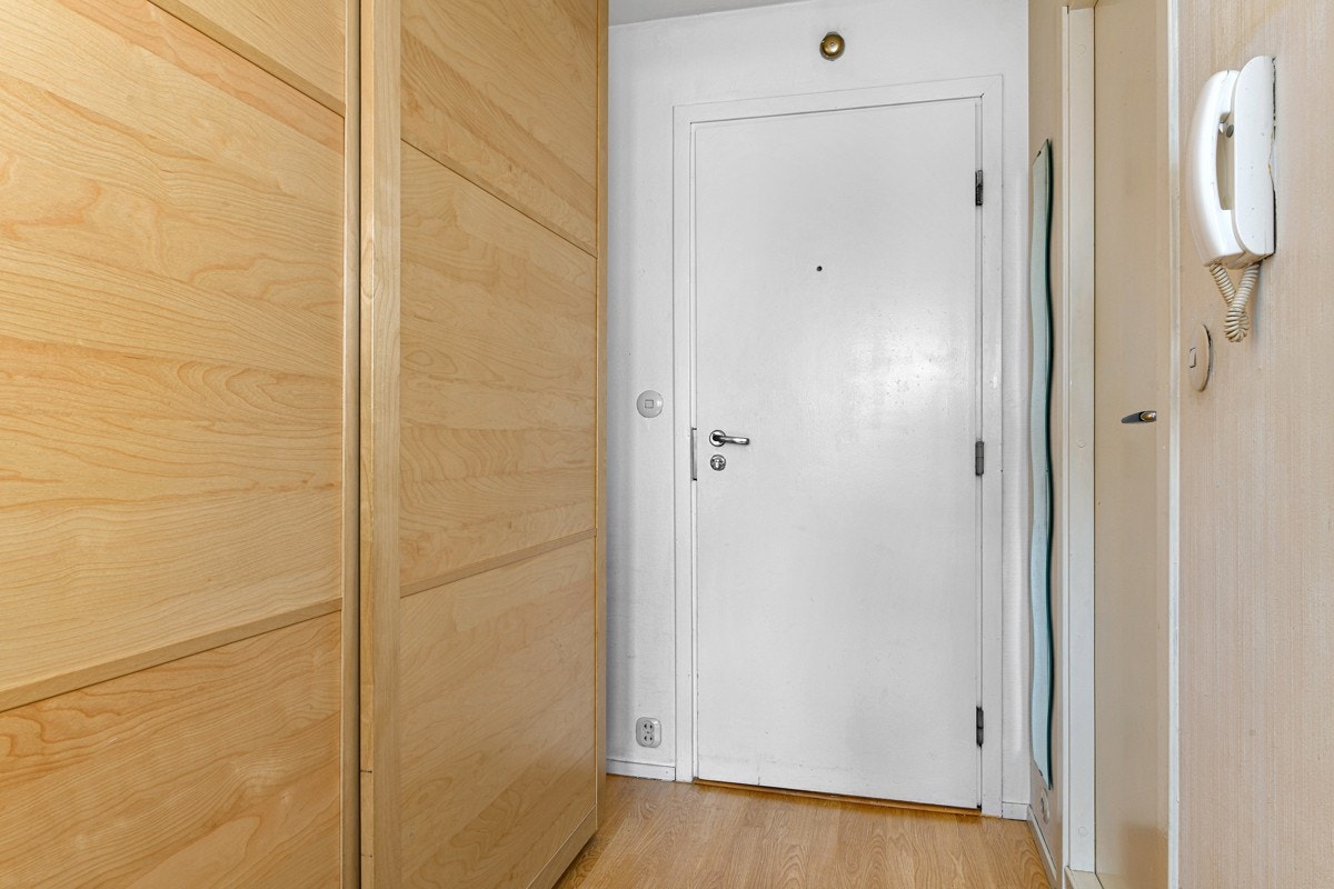 Leiligheten har en praktisk entré med laminatgulv, tapetsert og hvitmalte vegger, og porttelefon. Galleribilde