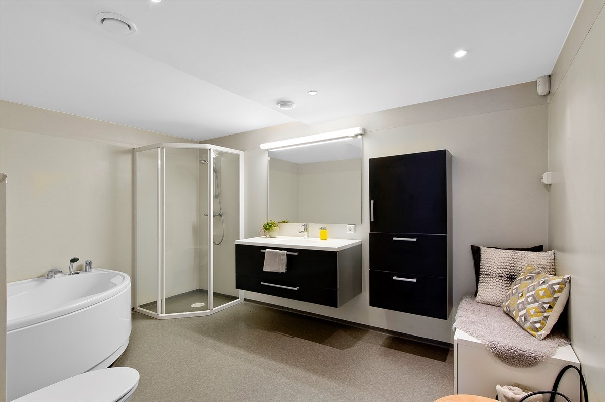 Stort og fint bad, med spotter i tak, dusj, badekar, vegghengt toalett og moderne innredning. Galleribilde