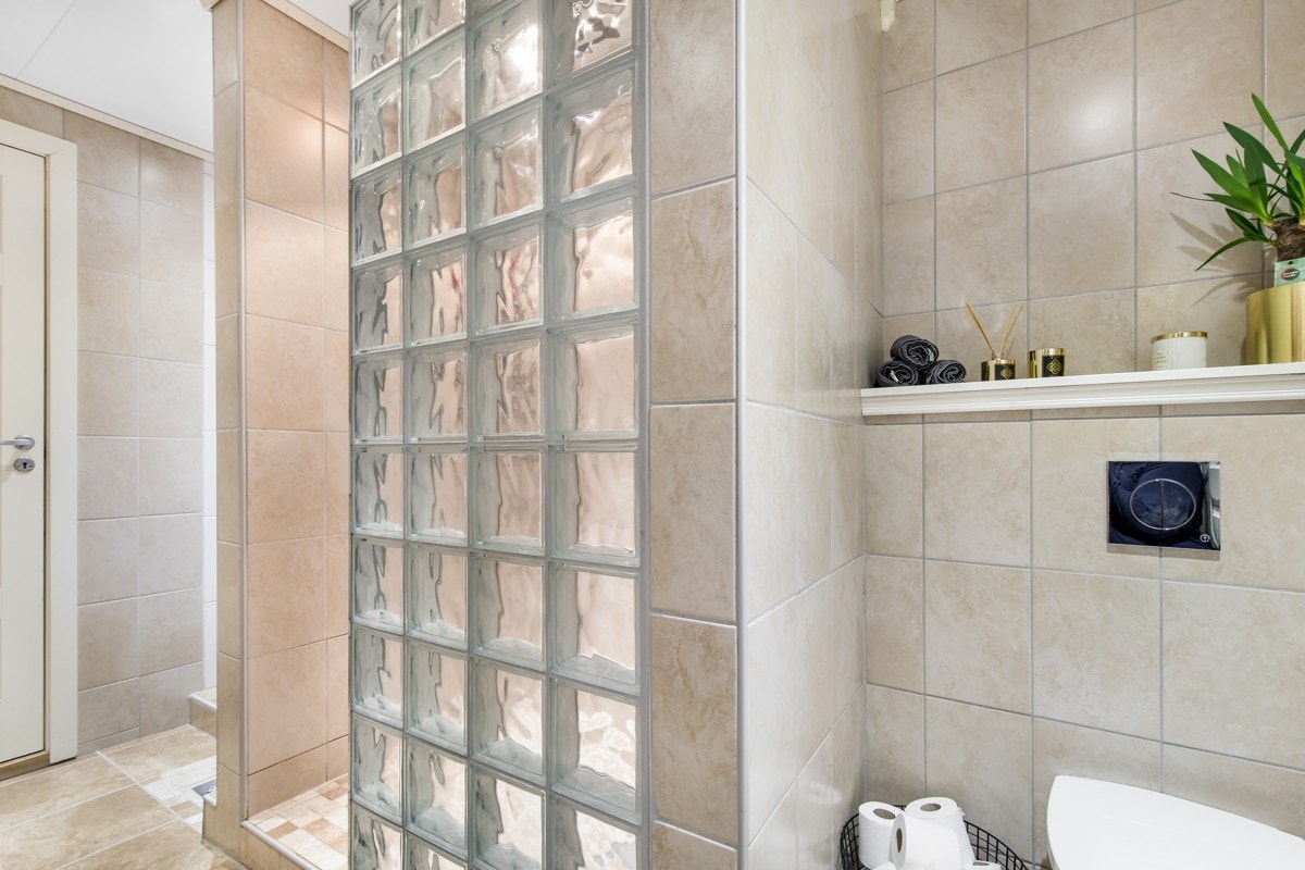 Dusjnisjen ligger skjermet bak en vegg av glassbyggerstein, og det er veggmontert toalett som ligger avskjermet i hjørnet av badet. Galleribilde