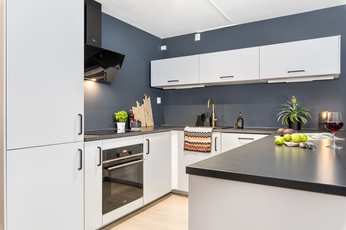 Lysegrå, glatte fronter er stilrent kombinert med grålaminert benkeplate. Alle hvitevarer er integrert og medfølger. Galleribilde