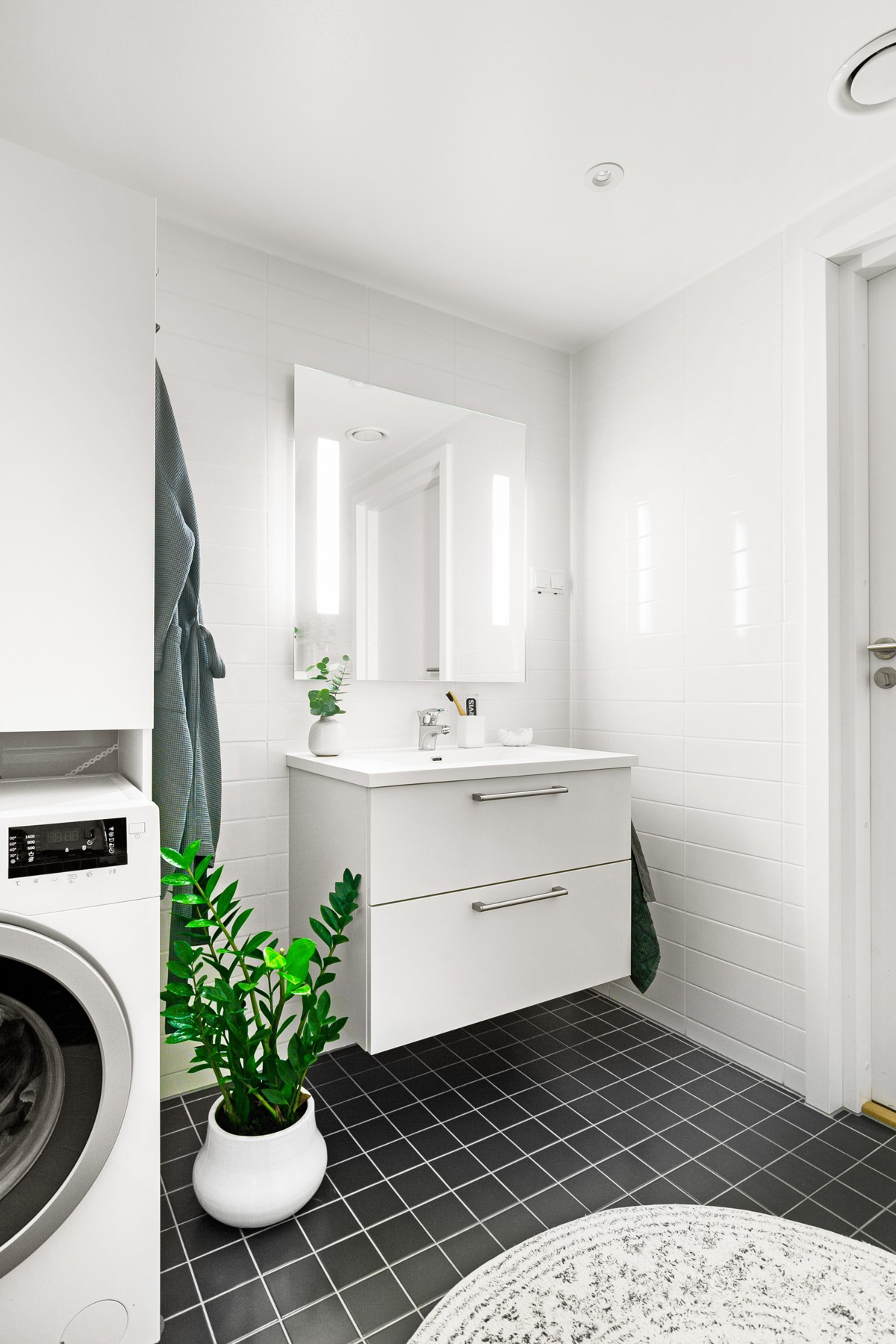 Servant og speil med lys - det er gjort tilvalg for særegne fliser som gir badet en pen finish