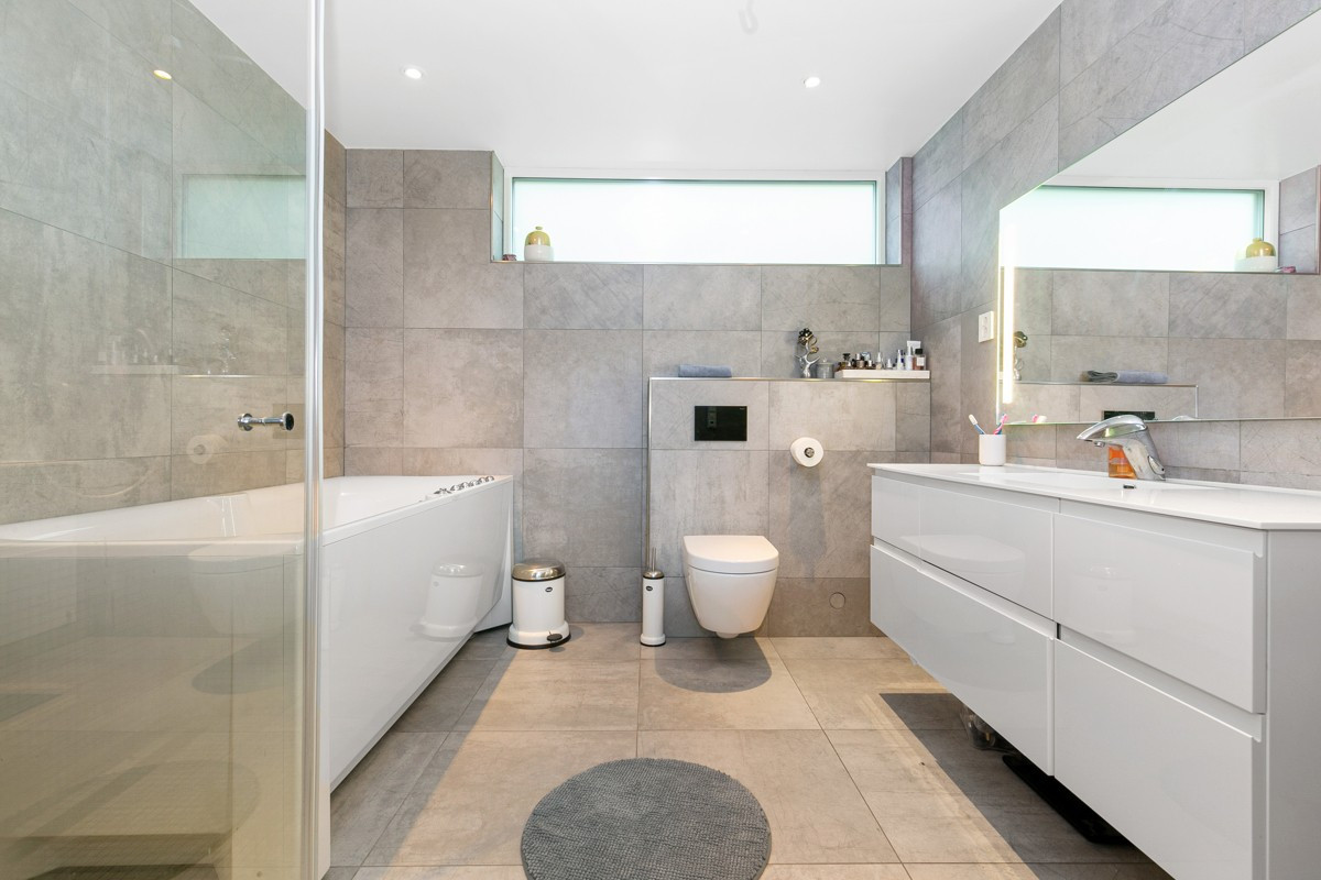 Badet er moderne innredet med vegghengt wc med elektrisk spyling og boblebadekar