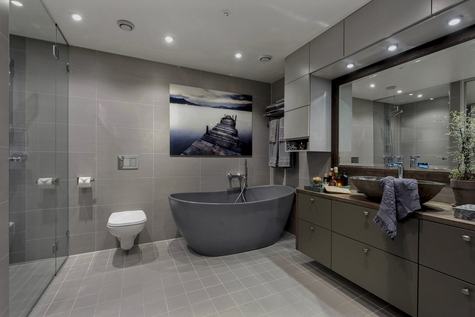 Stort og delikat bad med badekar i kompositt, vegghengt toalett og spesialtilpasset baderomsinnredning. Galleribilde