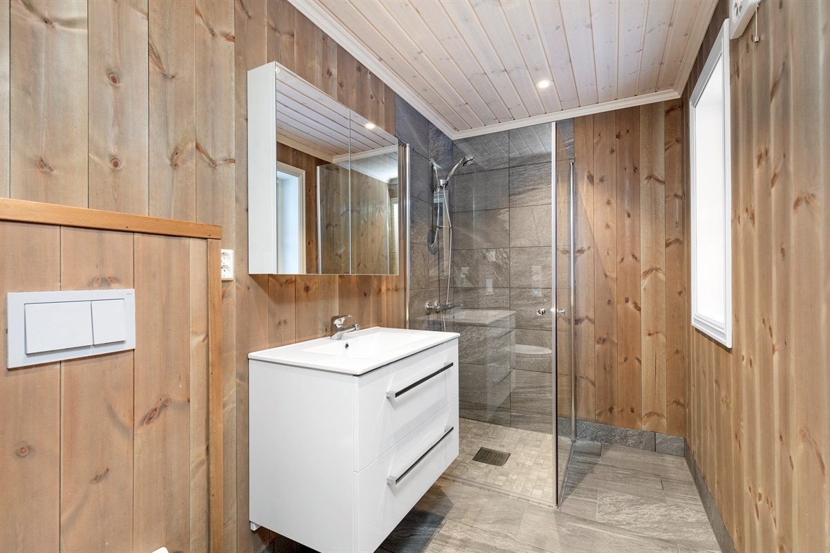 Inneholder vegghengt toalett, baderomsmøbel med speilskap og dusjhjørne. Galleribilde