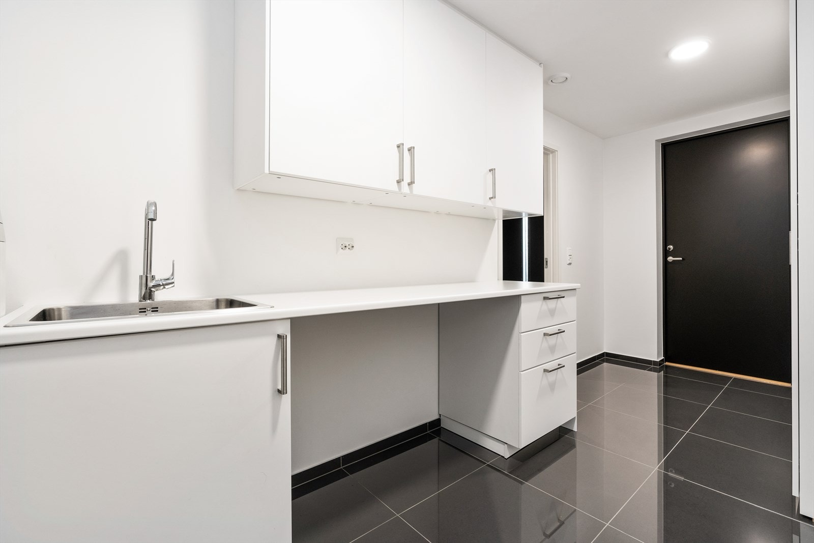 Stort og praktisk vaskerom som er innredet med arbeidsbenk, utslagsvask, over- og underskap Galleribilde