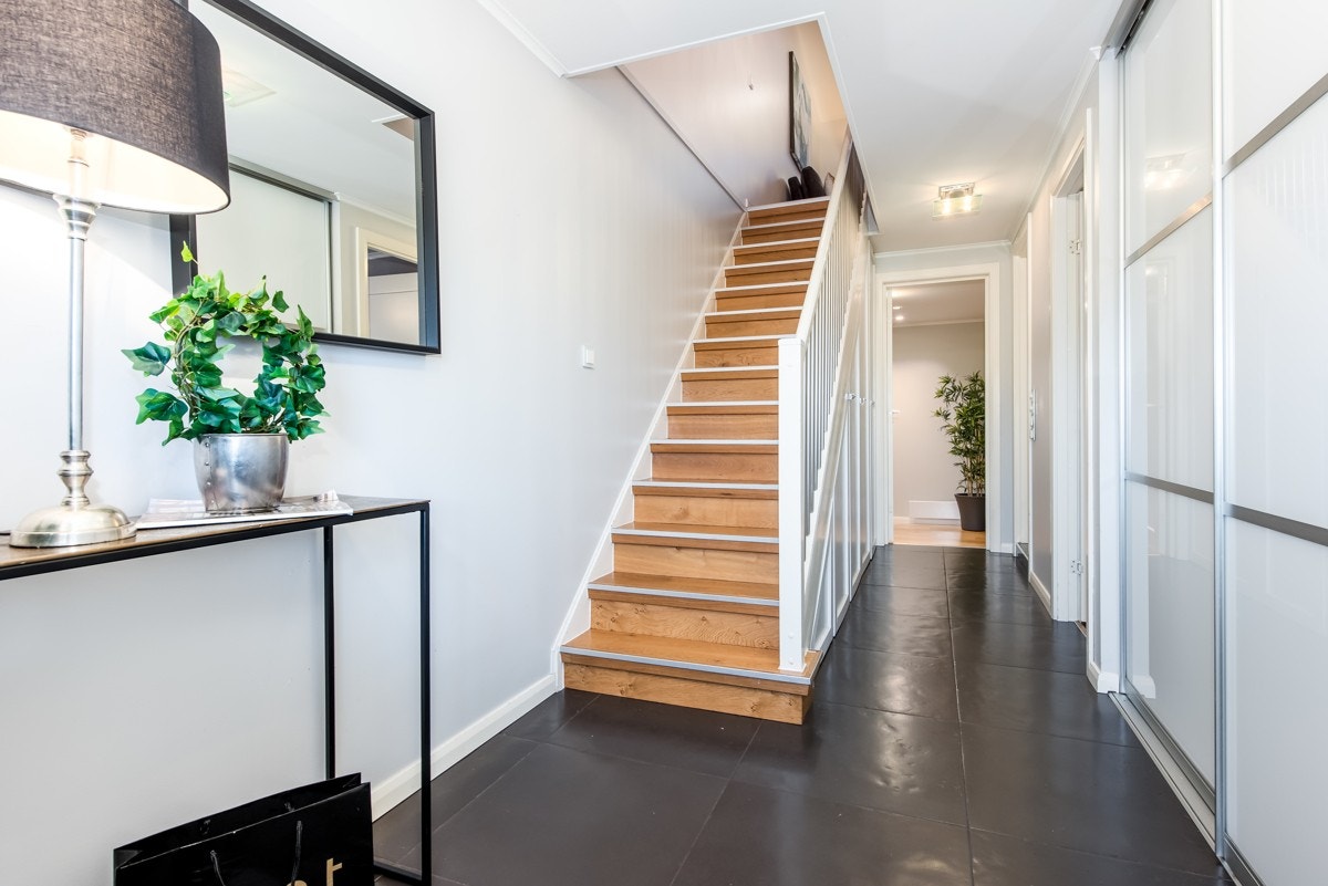 Lys og innbydende flislagt entré med varmekabler. Under trappen er det plassbygd garderobeskap, for god utnyttelse av oppbevaringsmuligheter. Galleribilde