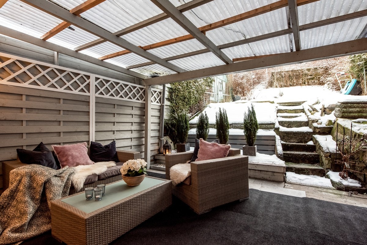 Overbygd terrasse med god plass til utemøbler - videre trapp opp til hage med gressplen. Galleribilde