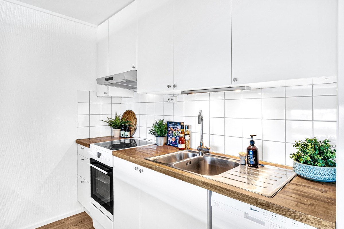 Kjøkkeninnredning av hvite glatte fronter med heltre benkeplate Galleribilde