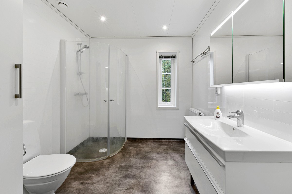 Badet har fin størrelse og er utstyrt med toalett og dusjhjørne med innfellbare glassdører. Galleribilde