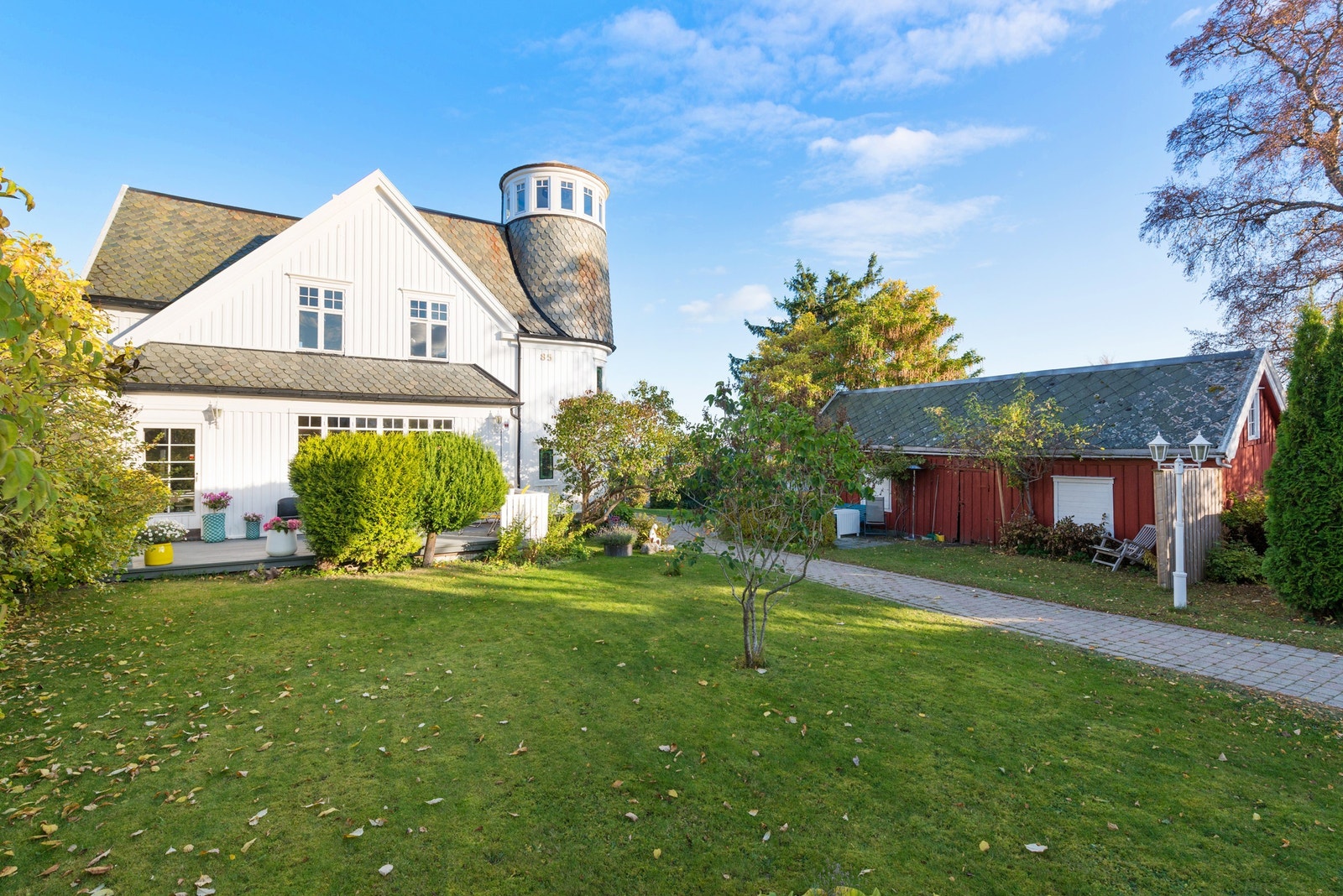 Tomten er velstelt og pent opparbeidet med plen, hekk, busker, frukttrær og adkomst med belegningsstein frem til huset. Galleribilde