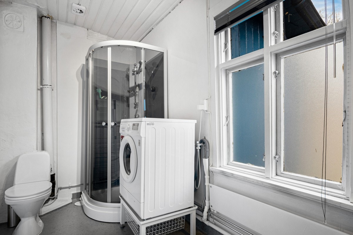 Bad med dusjkabinett, toalett og opplegg for vaskemaskin. Galleribilde