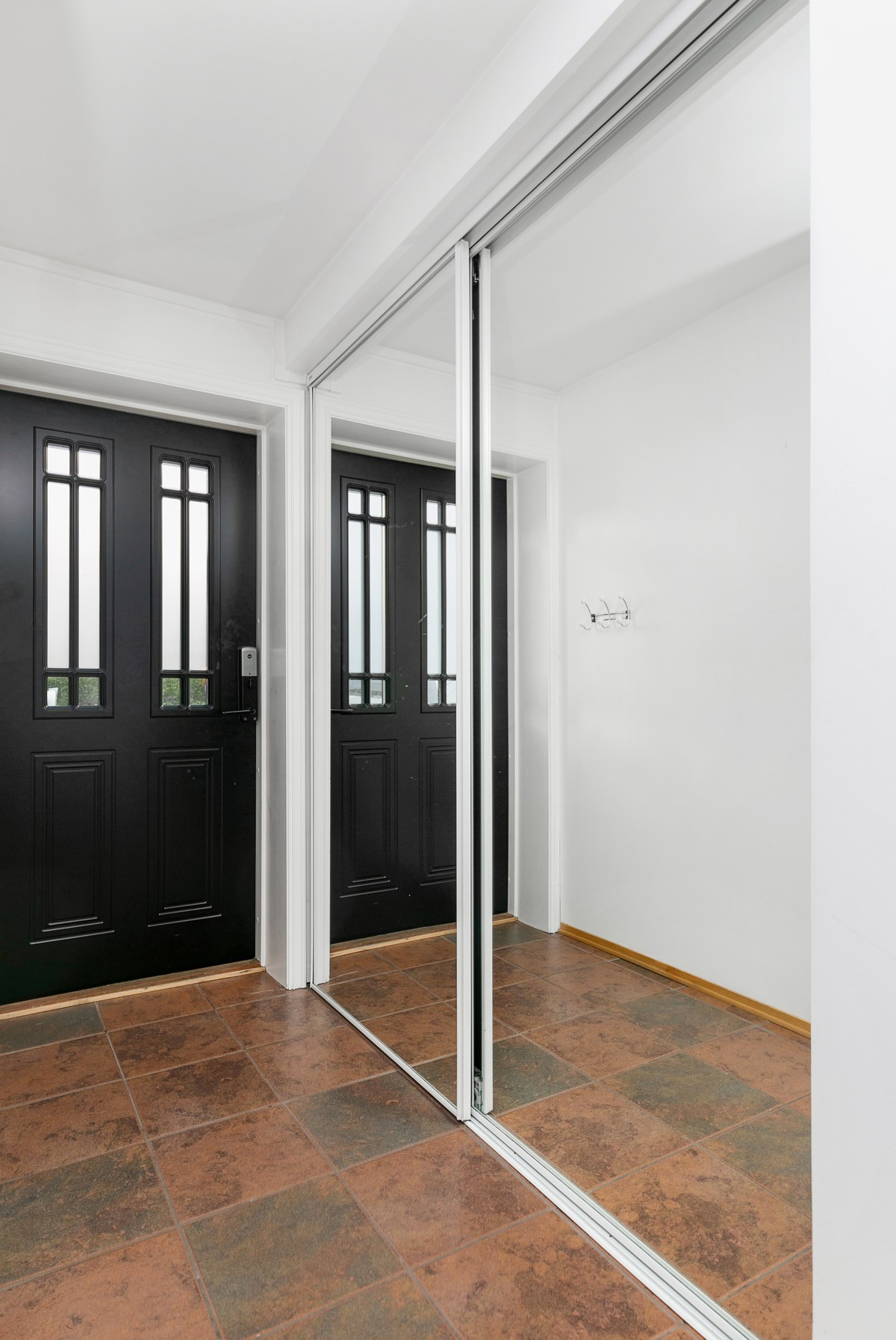 Flislagt entré med stor skyvedørsgarderobe med speil