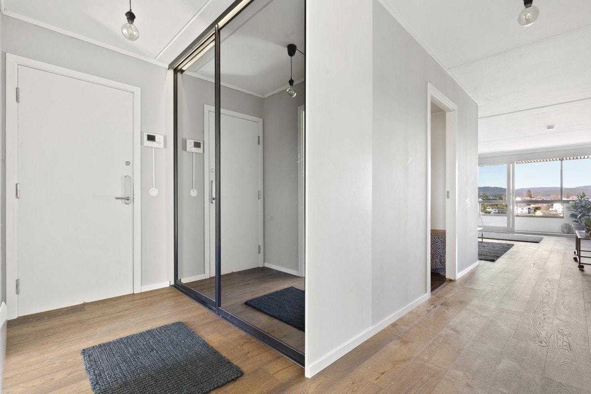 Leiligheten har et lyst og åpent inngangsparti med stor skyvedørsgarderobe med speilfronter som gir rikelig med oppbevaringsplass. Galleribilde