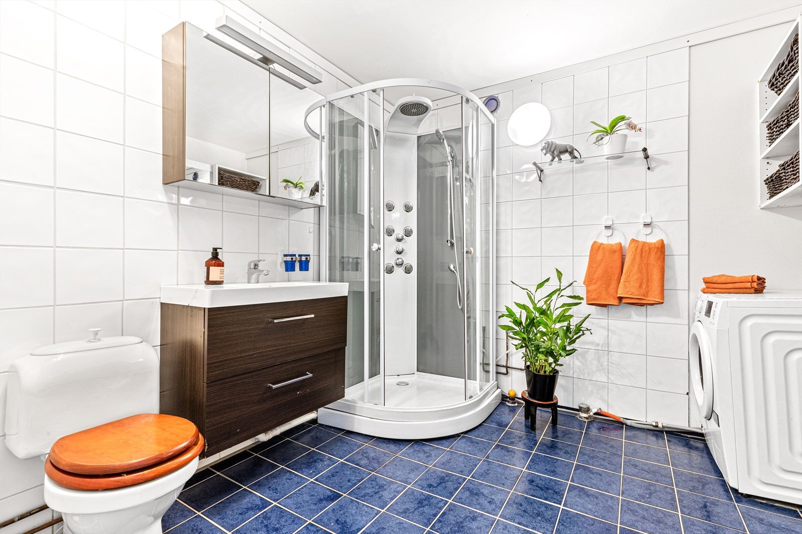 Stort baderom med dusjkabinett og opplegg for vaskemaskin. Nyere servant og overskap med lys. Galleribilde