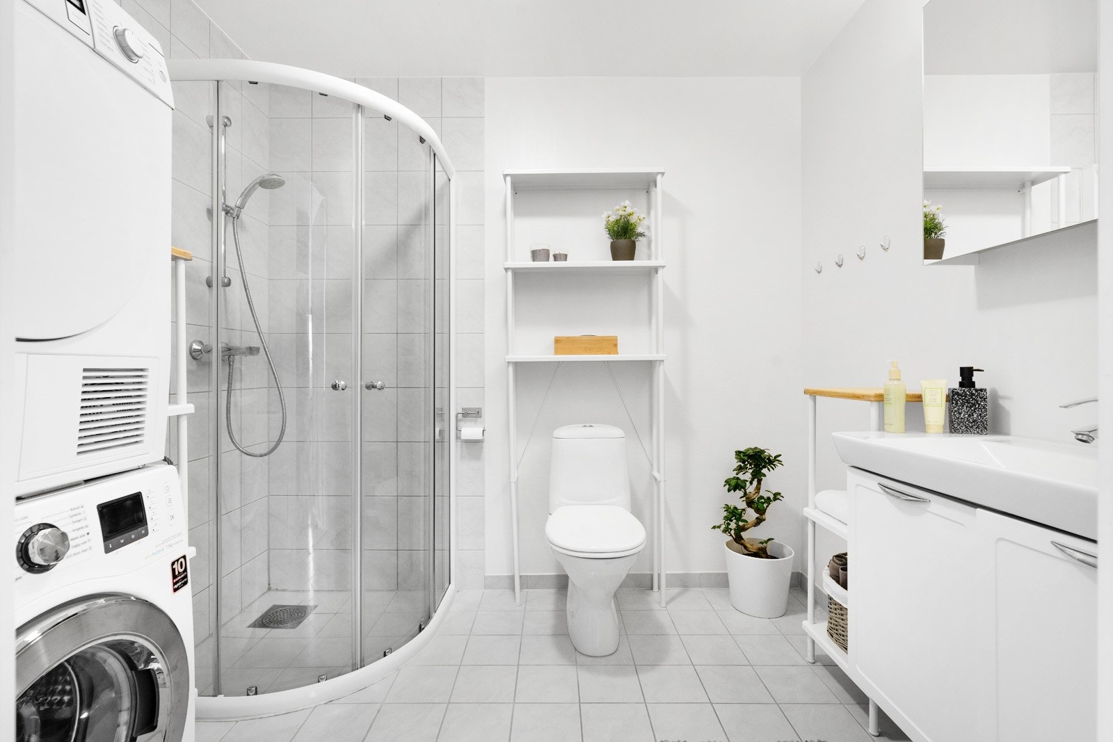 Badet er innredet med baderomsinnredning med servant, dusjhjørne, toalett og opplegg for vaskemaskin Galleribilde