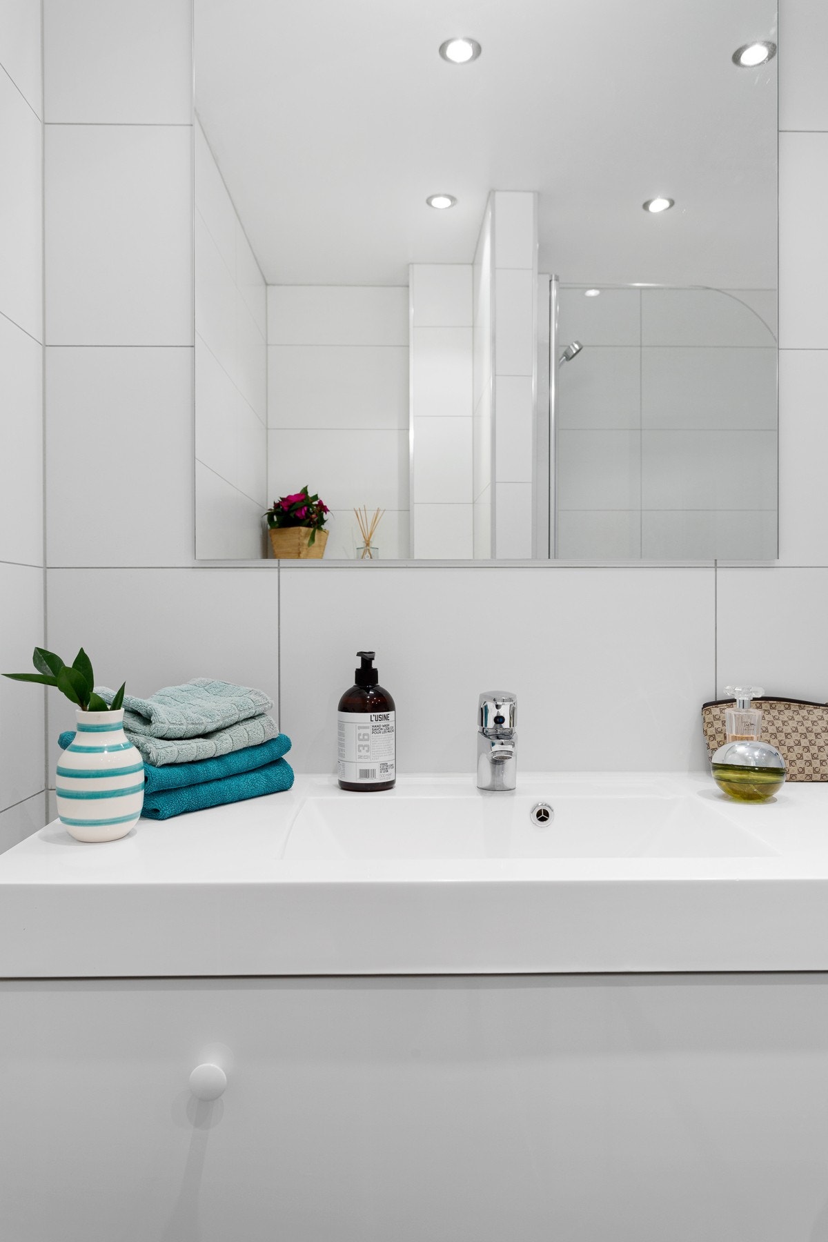 Badet har speil, heldekkende servant på hvitt skuffemøblement og et vegghengt toalett. Galleribilde