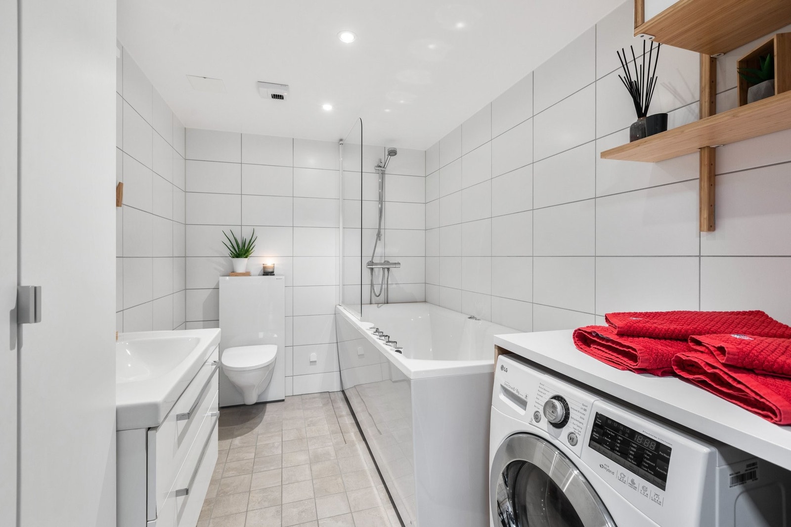 Stor baderom med vegghengt toalett og benkeplate over vaskemaskin Galleribilde