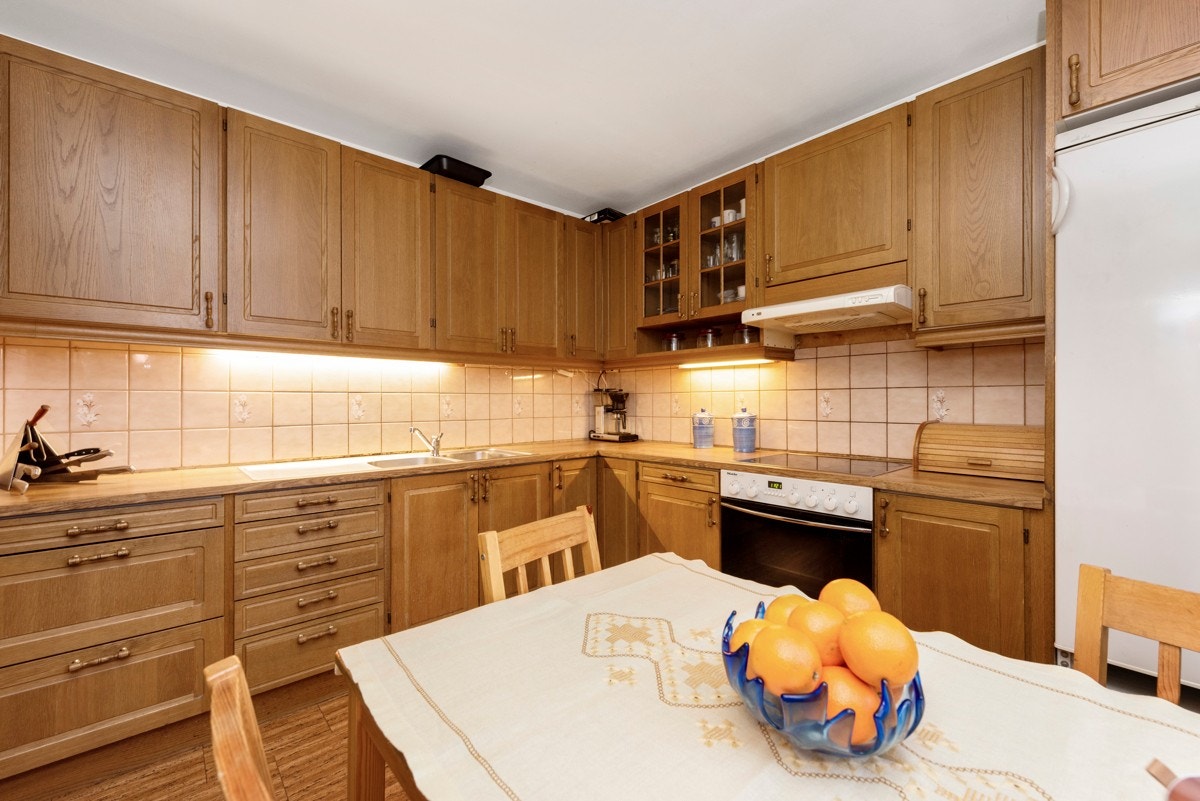 Kjøkkenet har innholdsrik innredning med profilerte eikefronter, ventilator, integrert ovn og topp. Galleribilde