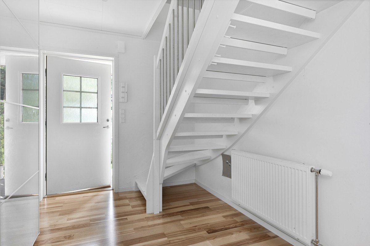 Entreen har parkettgulv og hvitmalte vegger, noe som står fint i stil med resten av boligen. Yttertøy og sko oppbevares lettvint i en skyvedørsgarderobe med speilfronter. Galleribilde