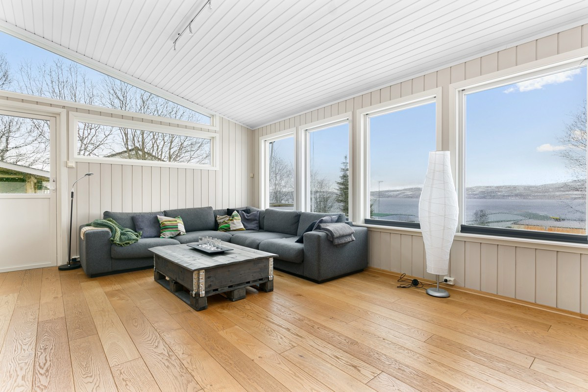 God plass til stor sofagruppe i boligens sørvestlige hjørne - døren til venstre går ut til solfylt terrasse