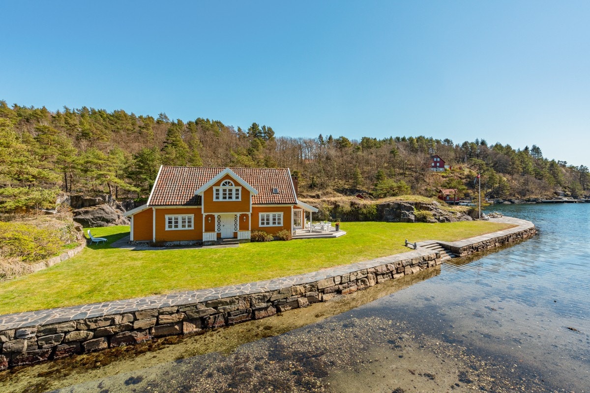 Lang steinsatt brygge og store plener utenfor den store hytten Galleribilde