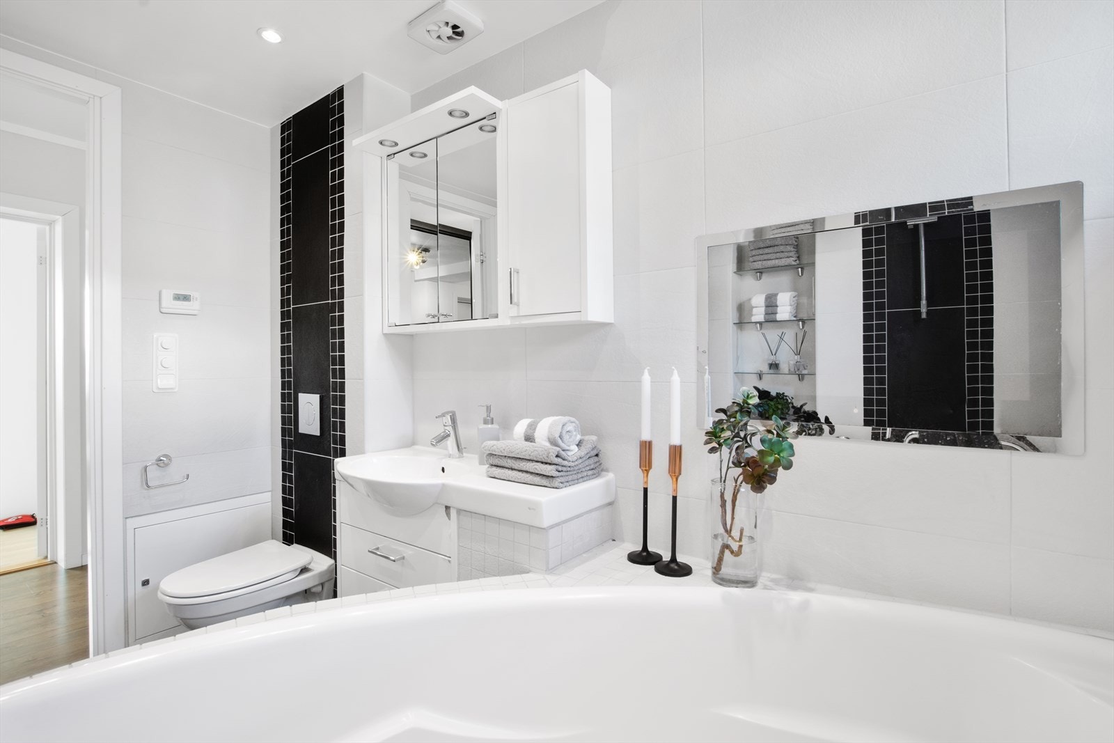 Pent flislagt bad med boblebadekar, servantinnredning, veggmontert wc, veggmontert håndkletørker. Innebygget TV på vegg. Galleribilde