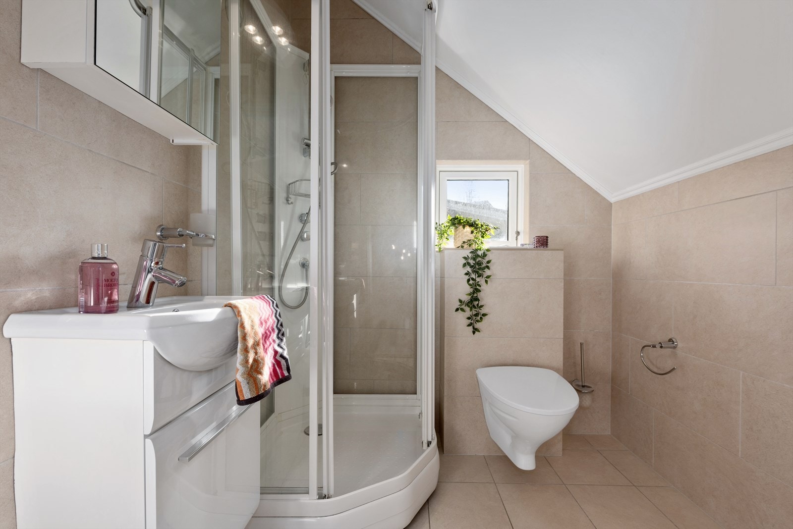 Lunt og delikat bad med gulvvarme. Innredningen består av servant med underskap og overskap med speil, dusjkabinett og vegghengt toalett. Galleribilde