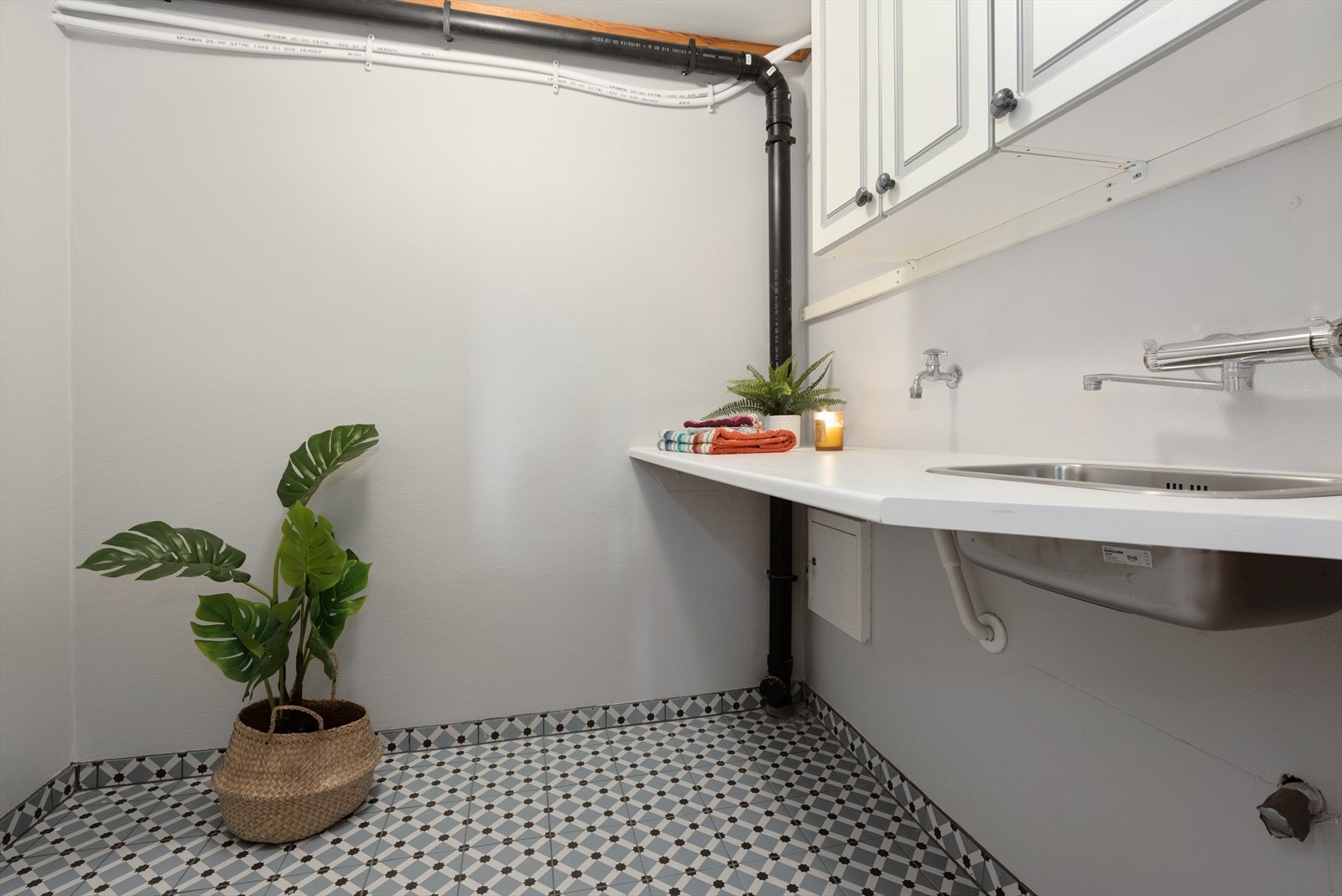 Boligen har et praktisk vaskerom med laminat benkeplate med nedfelt kum i stål og overskap. Opplegg for vaskemaskin. Galleribilde