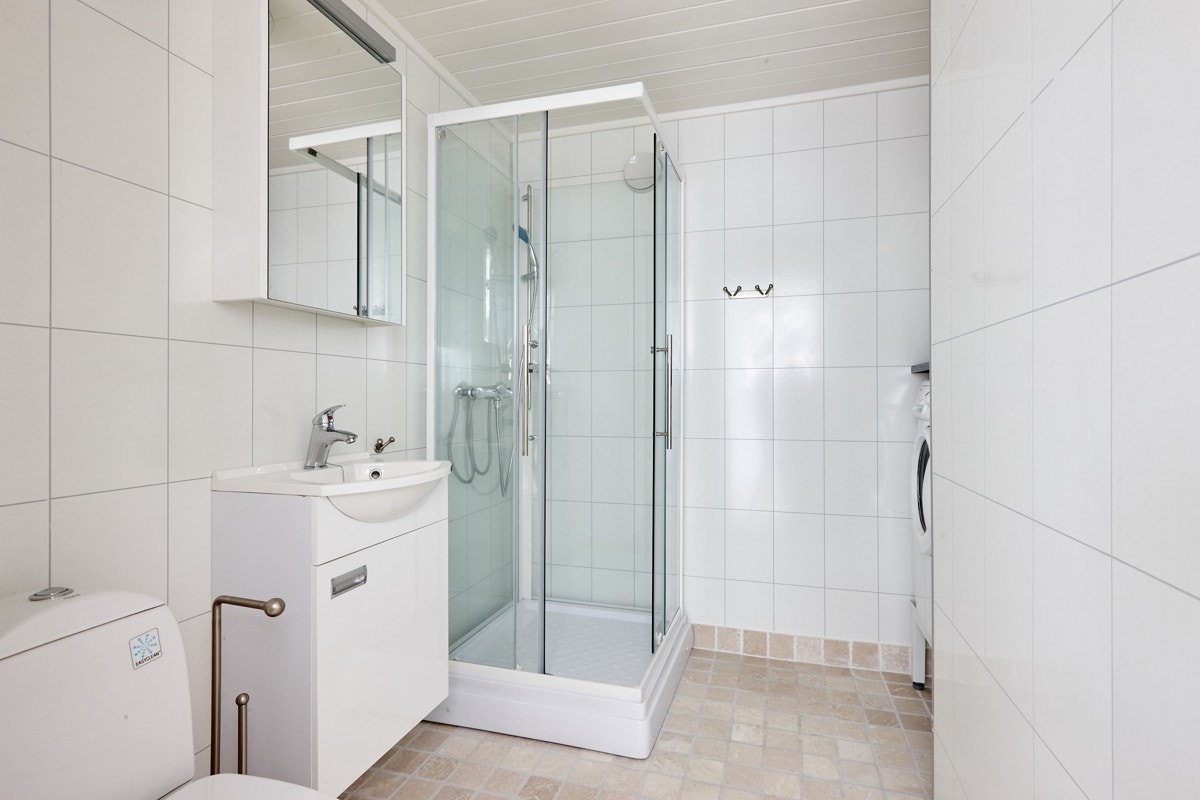 Bad med innredning, dusjkabinett, toalett og opplegg for vaskemaskin. Varme i gulv Galleribilde