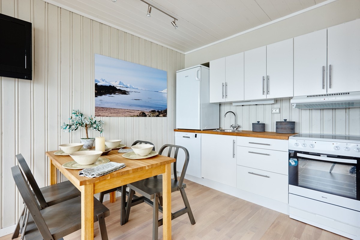 Kjøkkeninnredning med lyse slette fronter, skuffer og skap, og benke plate i oljet eik. Galleribilde