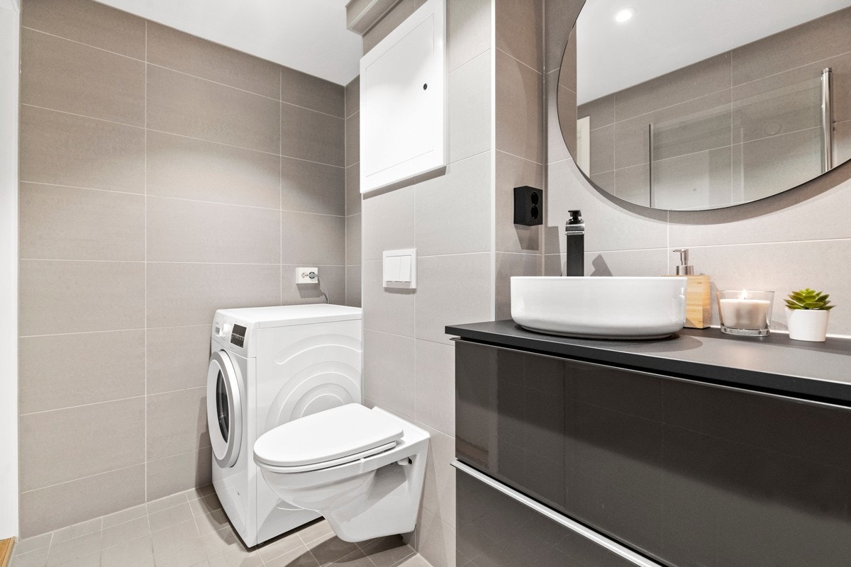 Badet er utstyrt med fastmonterte svingbare dusjvegger, hånd- og regnfallsdusj. Videre har du vegghengt servantskap med slette fronter. Galleribilde