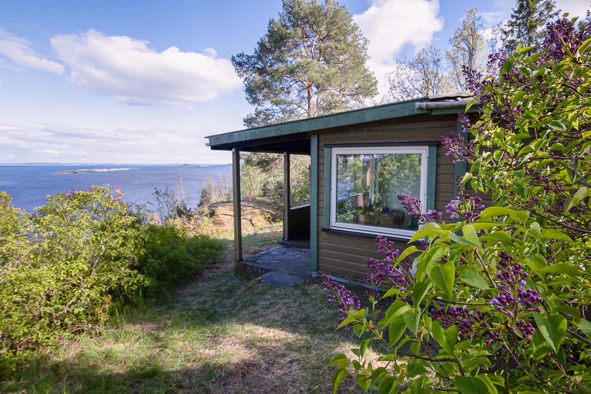 Syriner blir plantet rundt hytta, og naturen bidrar med liljekonvaller og markjordbær. Galleribilde