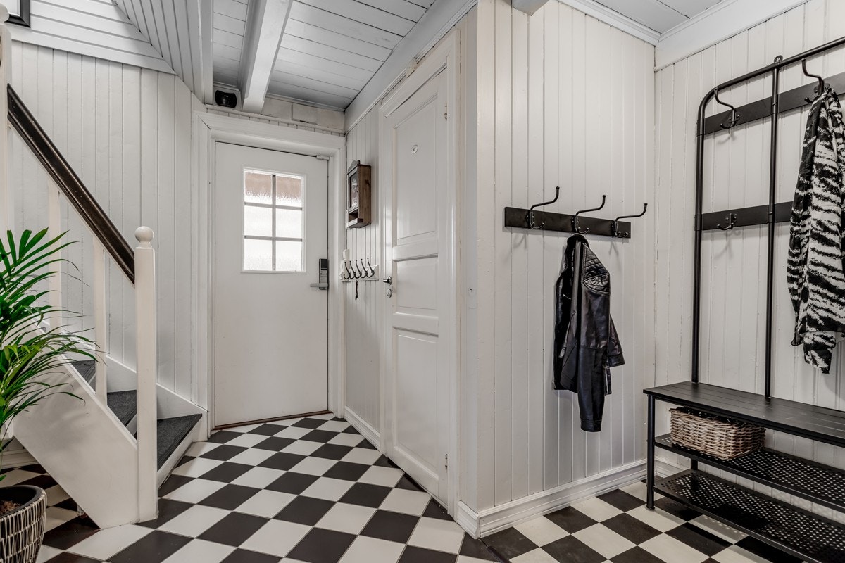 Den trivelige entreen har gulvvarme, et stilrent fargevalg, flere knagger og en svingtrapp opp til andre etasje. Galleribilde