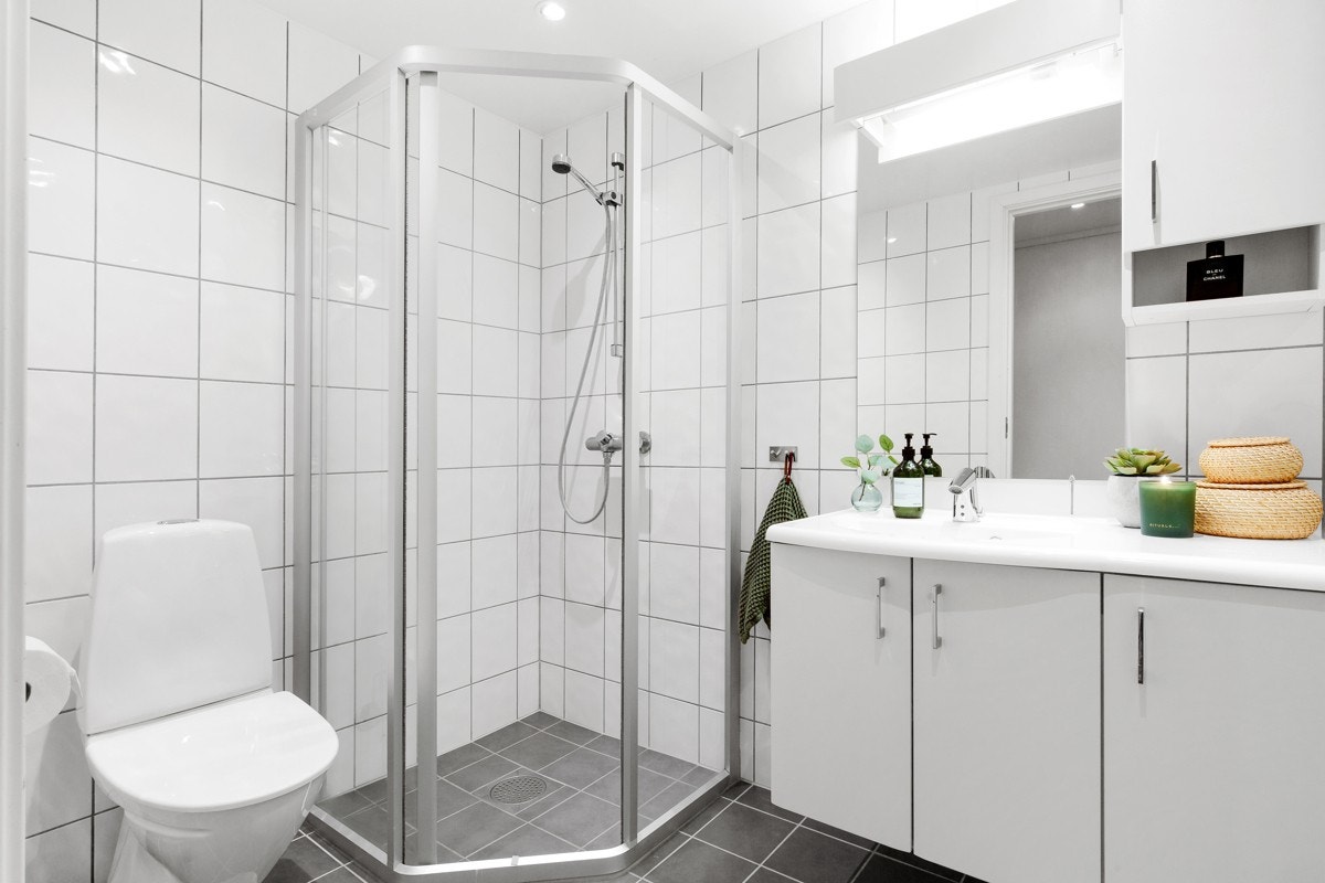 Badet inneholder wc, dusjhjørne, servant med over- og underskap og opplegg for vaskemaskin og tørketrommel Galleribilde