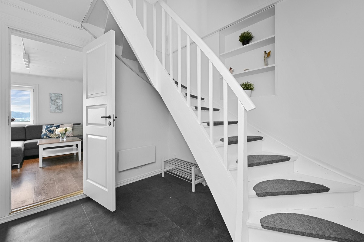 En hvitmalt trapp med trappeneser svinger seg opp til andre etasje. Galleribilde